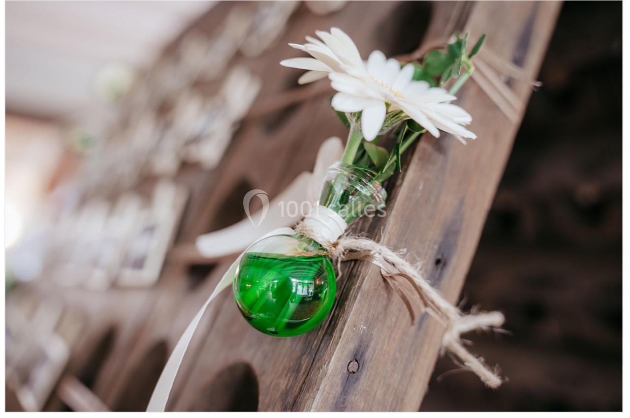 Location salle Mouscron (Hainaut) - Le Belvédère #8 Petit vase en verre vert contenant une fleur blanche, attaché à une structure en bois avec une corde.