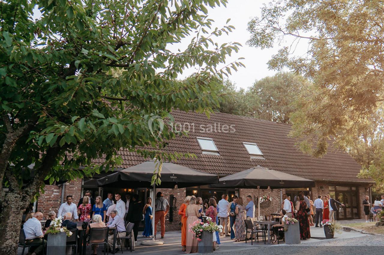 Location salle Mouscron (Hainaut) - Le Belvédère #4 Groupe de personnes rassemblées sur une terrasse ombragée devant un bâtiment en briques entouré d'arbres.
