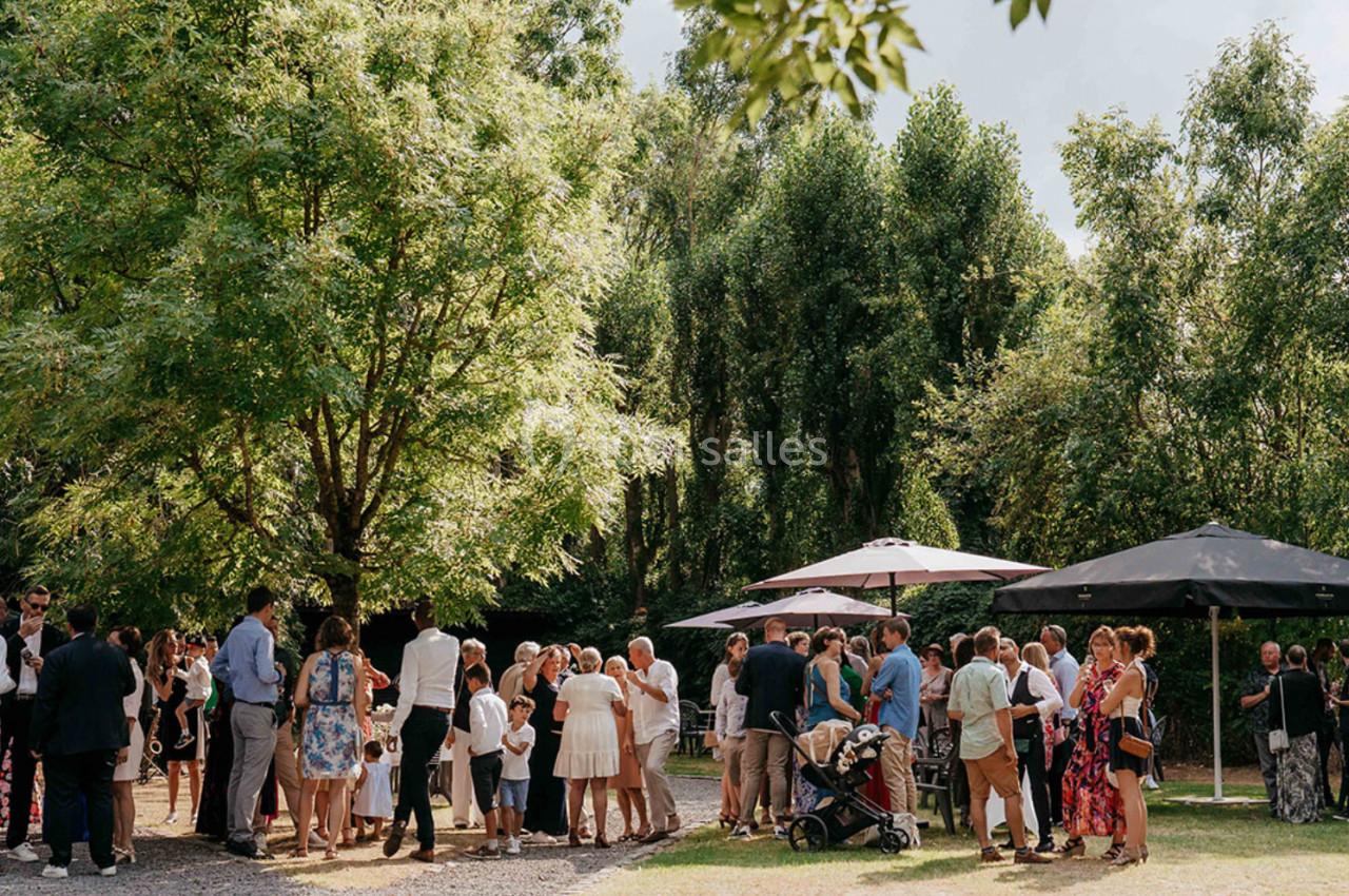 Location salle Mouscron (Hainaut) - Le Belvédère #5 Groupe de personnes rassemblées en extérieur sous des arbres, avec des parasols et une ambiance conviviale.