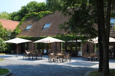 Miniature Location salle Mouscron (Hainaut) - Le Belvédère #3 Terrasse extérieure d'un restaurant avec des tables et chaises sur un sol en pierre, entourée de verdure et arbres.