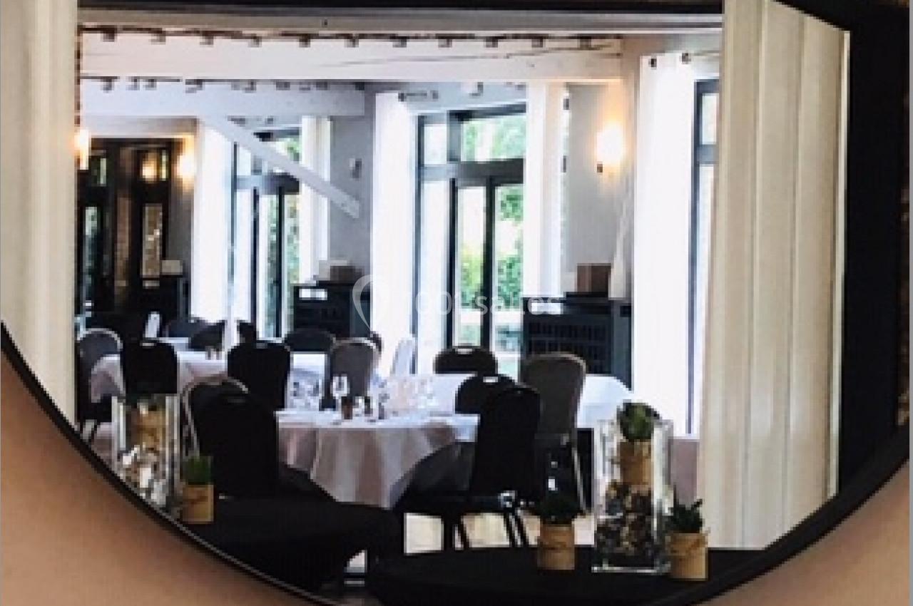 Location salle Mouscron (Hainaut) - Le Belvédère #11 Reflet d'une salle de restaurant élégante avec tables dressées, vu à travers un miroir rond encadré de noir.