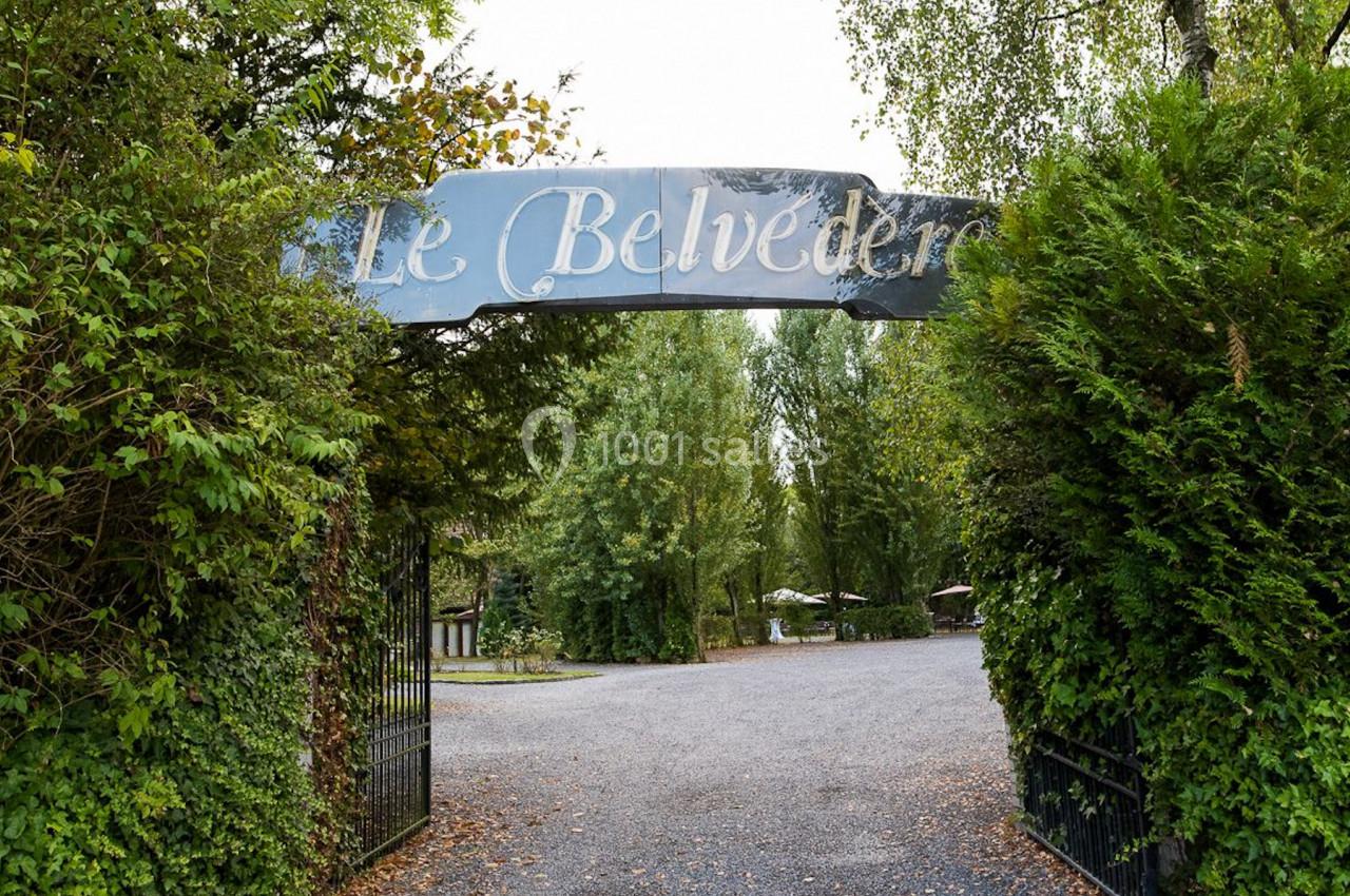 Location salle Mouscron (Hainaut) - Le Belvédère #2 Entrée d'un lieu nommé ’Le Belvédère’, avec une arche métallique entourée de verdure et un chemin menant à l'intérieur.