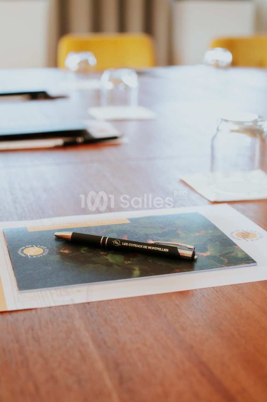 Stylo noir posé sur une feuille imprimée avec des verres et des dossiers sur une table en bois.