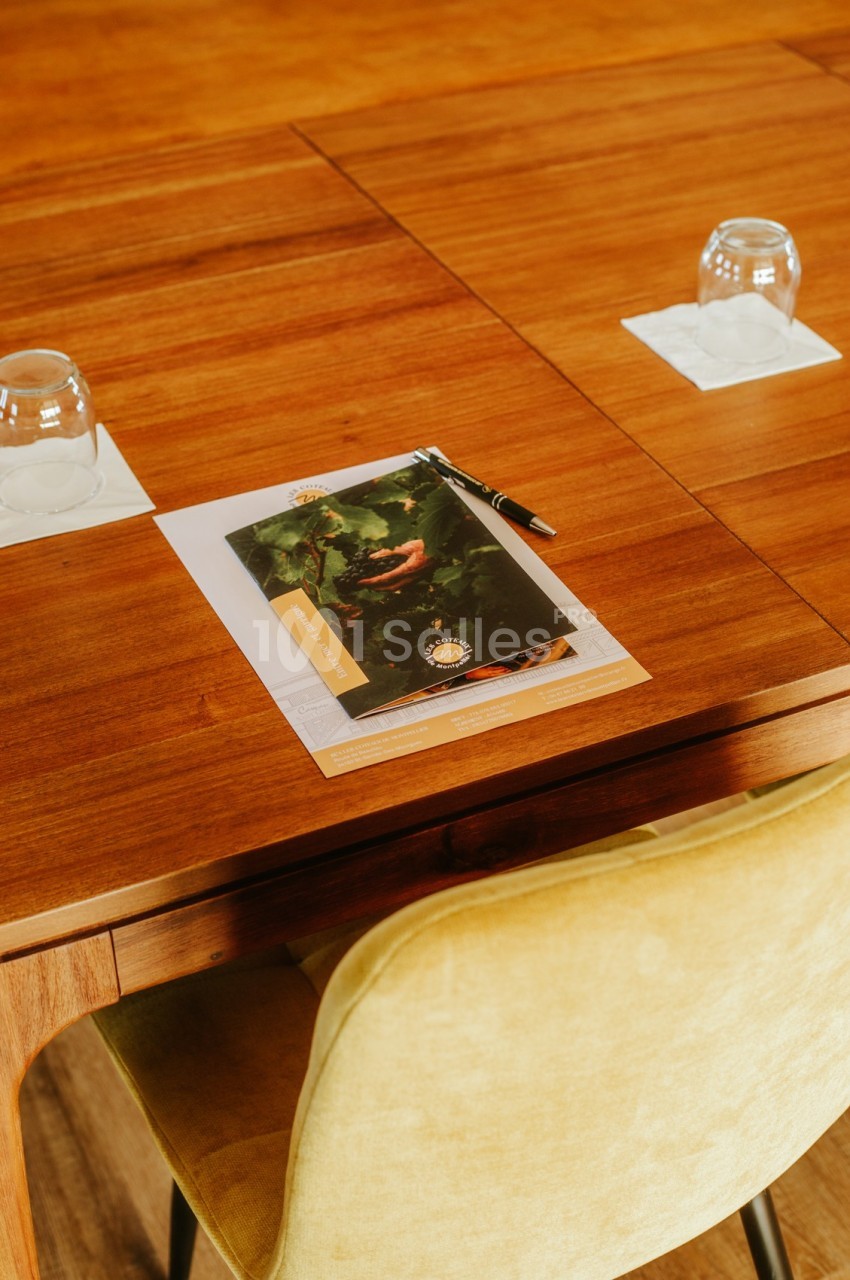 Un document avec un stylo posé sur une table en bois, entouré de deux verres retournés.