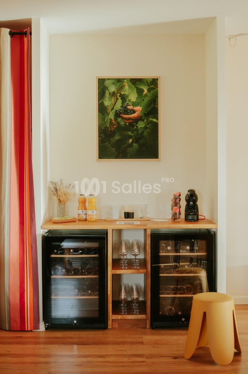 Deux mini-réfrigérateurs noirs sous un comptoir en bois avec boissons, verres et une machine à café.