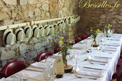 Groupe de personnes rassemblées dans une cour extérieure verdoyante devant un bâtiment en pierre avec des volets bleus.