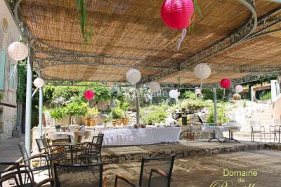 Groupe de personnes rassemblées dans une cour extérieure verdoyante devant un bâtiment en pierre avec des volets bleus.