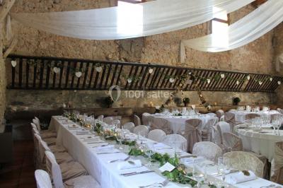 Groupe de personnes rassemblées dans une cour extérieure verdoyante devant un bâtiment en pierre avec des volets bleus.
