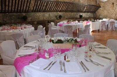 Groupe de personnes rassemblées dans une cour extérieure verdoyante devant un bâtiment en pierre avec des volets bleus.
