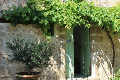 Groupe de personnes rassemblées dans une cour extérieure verdoyante devant un bâtiment en pierre avec des volets bleus.