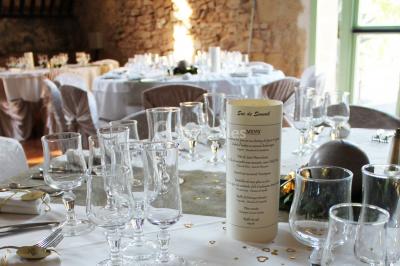 Groupe de personnes rassemblées dans une cour extérieure verdoyante devant un bâtiment en pierre avec des volets bleus.