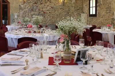 Groupe de personnes rassemblées dans une cour extérieure verdoyante devant un bâtiment en pierre avec des volets bleus.