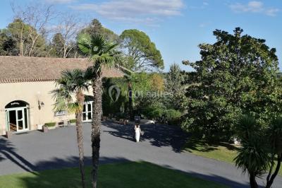 Groupe de personnes rassemblées dans une cour extérieure verdoyante devant un bâtiment en pierre avec des volets bleus.