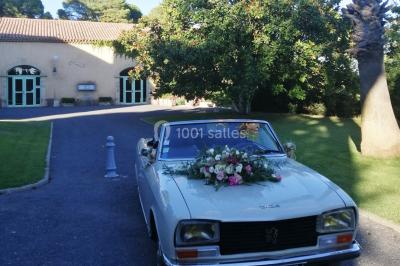 Groupe de personnes rassemblées dans une cour extérieure verdoyante devant un bâtiment en pierre avec des volets bleus.