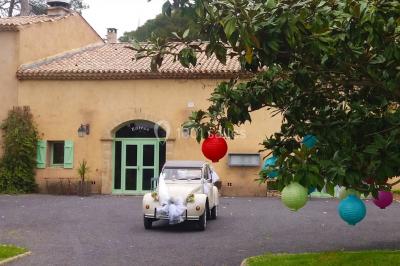 Groupe de personnes rassemblées dans une cour extérieure verdoyante devant un bâtiment en pierre avec des volets bleus.
