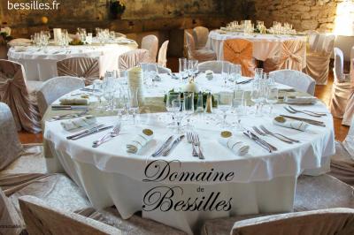 Groupe de personnes rassemblées dans une cour extérieure verdoyante devant un bâtiment en pierre avec des volets bleus.