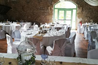 Groupe de personnes rassemblées dans une cour extérieure verdoyante devant un bâtiment en pierre avec des volets bleus.