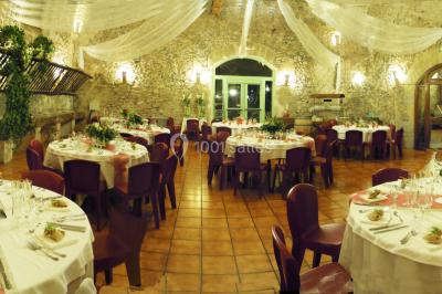 Groupe de personnes rassemblées dans une cour extérieure verdoyante devant un bâtiment en pierre avec des volets bleus.