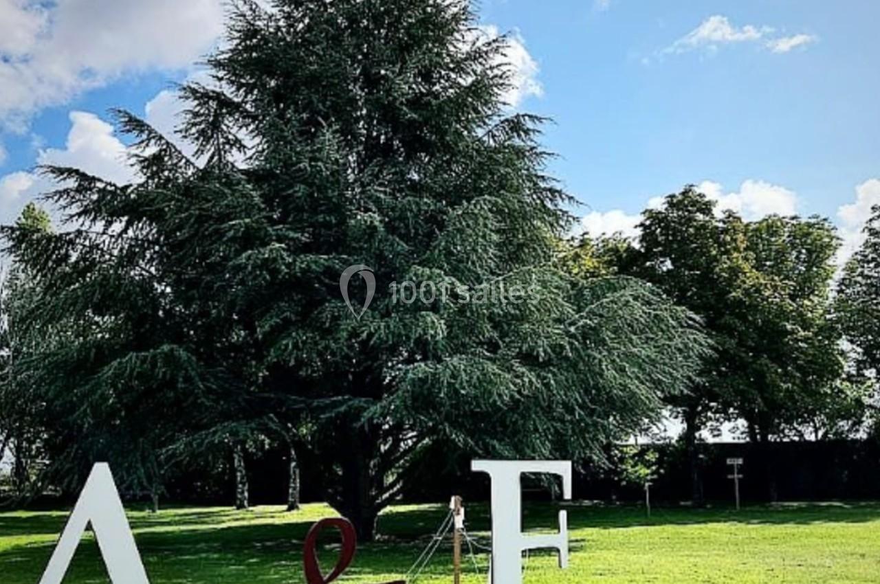 Location salle Villampuy (Eure-et-Loir) - Domaine de la Rainville #37 Lettres géantes ’A & F’ posées sur une pelouse verte, avec un grand arbre et un ciel bleu en arrière-plan.