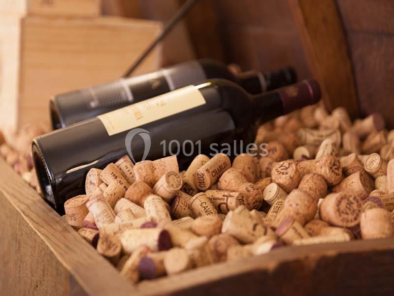 Deux bouteilles de vin rouge posées sur un lit de bouchons en liège dans une caisse en bois.