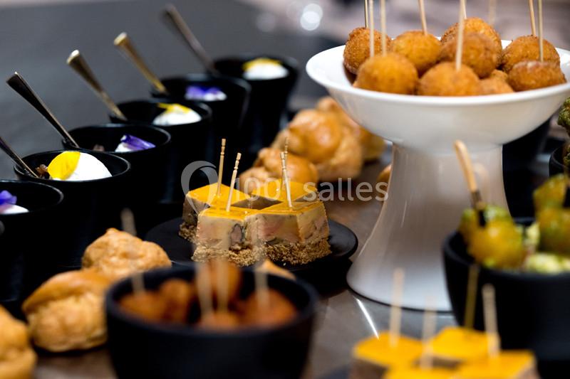 Assortiment de bouchées salées présentées sur des plateaux, incluant verrines, brochettes et amuse-bouches variés.