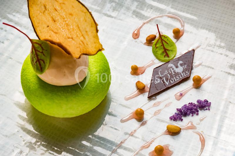 Dessert raffiné composé d'une mousse verte, d'une tuile, d'une crème glacée et de décorations artistiques en chocolat.