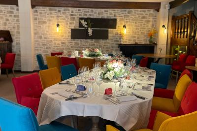 Miniature Location salle Voisins-le-Bretonneux (Yvelines) - La Ferme de Voisins #8 Table dressée avec des verres, couverts et serviettes, entourée de chaises colorées dans une salle lumineuse avec…