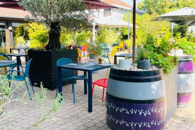 Miniature Location salle Voisins-le-Bretonneux (Yvelines) - La Ferme de Voisins #10 Table dressée avec des verres, couverts et serviettes, entourée de chaises colorées dans une salle lumineuse avec…