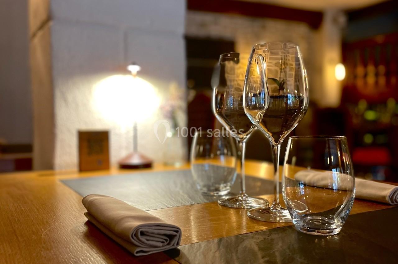 Table dressée avec des verres et des serviettes dans un restaurant à l'éclairage tamisé.