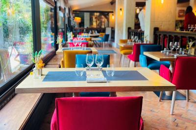 Miniature Location salle Voisins-le-Bretonneux (Yvelines) - La Ferme de Voisins #20 Table dressée avec des verres, couverts et serviettes, entourée de chaises colorées dans une salle lumineuse avec…