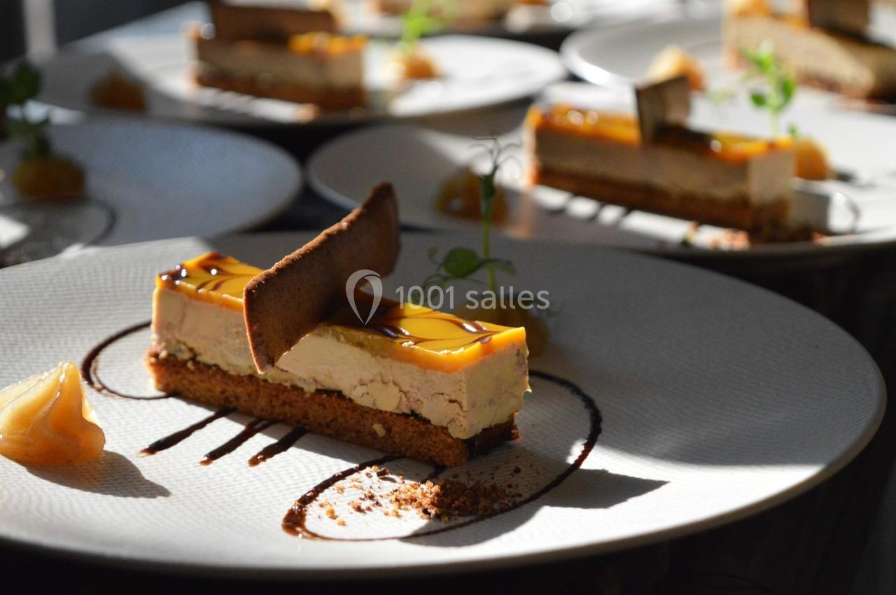 Part de gâteau au caramel sur une assiette blanche, décorée de sauce chocolat et d'une touche de verdure.
