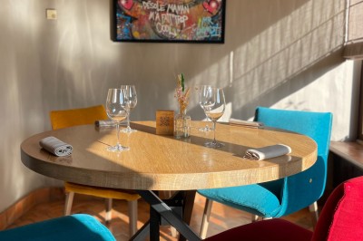 Miniature Location salle Voisins-le-Bretonneux (Yvelines) - La Ferme de Voisins #37 Table dressée avec des verres, couverts et serviettes, entourée de chaises colorées dans une salle lumineuse avec…