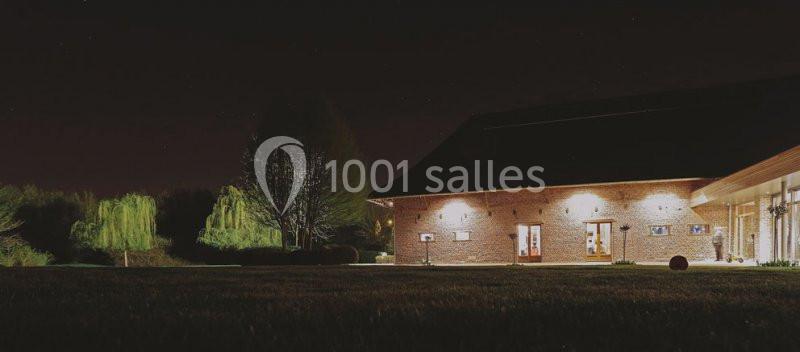 Location salle Brunehaut (Hainaut) - Le Clos de la Conciergerie #2 Bâtiment en briques éclairé la nuit, entouré d'arbres et d'une pelouse sombre.