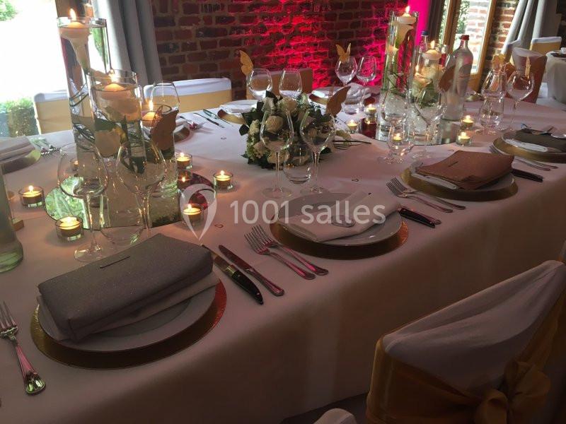 Location salle Brunehaut (Hainaut) - Le Clos de la Conciergerie #14 Table élégamment dressée avec nappes blanches, vaisselle raffinée, bougies allumées et décoration florale.