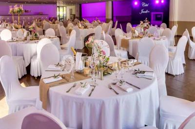 Une mariée lance son bouquet à un groupe de femmes rassemblées dans un jardin lors d'une réception en soirée.