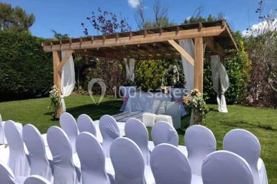 Une mariée lance son bouquet à un groupe de femmes rassemblées dans un jardin lors d'une réception en soirée.