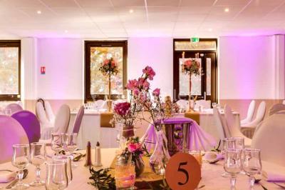 Une mariée lance son bouquet à un groupe de femmes rassemblées dans un jardin lors d'une réception en soirée.