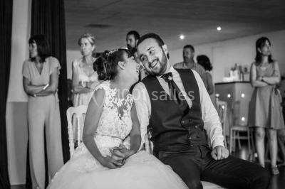 Une mariée lance son bouquet à un groupe de femmes rassemblées dans un jardin lors d'une réception en soirée.