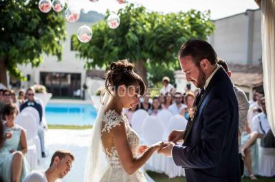 Une mariée lance son bouquet à un groupe de femmes rassemblées dans un jardin lors d'une réception en soirée.