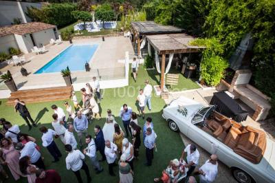 Une mariée lance son bouquet à un groupe de femmes rassemblées dans un jardin lors d'une réception en soirée.