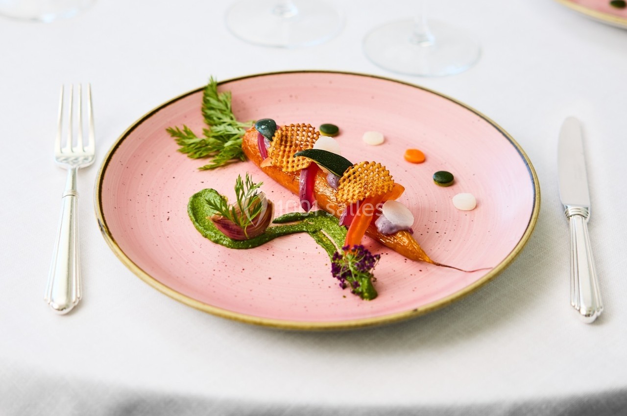 Assiette gastronomique avec présentation artistique de légumes colorés, purée verte et décorations raffinées.