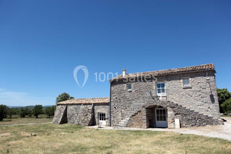 Maison en pierre avec escalier extérieur, située dans un paysage rural sous un ciel bleu dégagé.