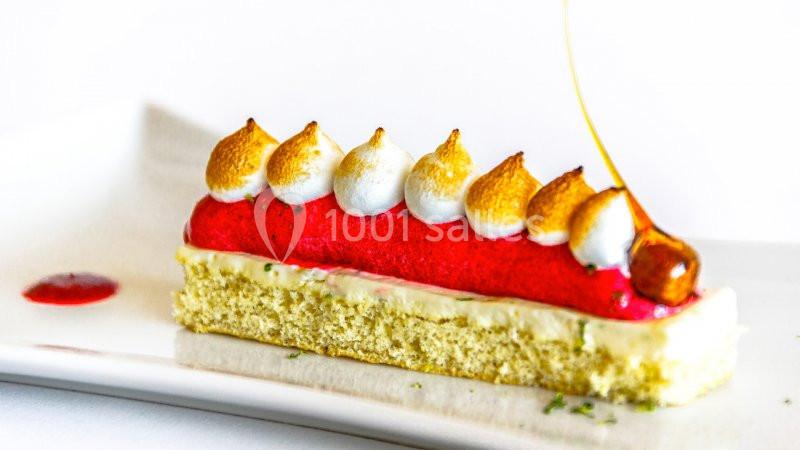 Pâtisserie composée d'une base moelleuse, d'une mousse rouge, de meringues dorées et d'un décor en caramel.