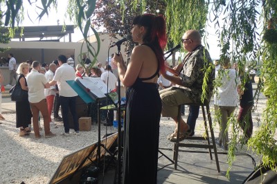 Miniature DJ Pézilla-la-Rivière (Pyrénées-Orientales) - Cleanjack #5 Un duo musical se produit sur une scène intérieure avec guitare et chant, devant un public assis.