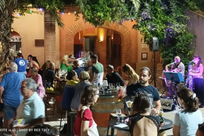 Miniature DJ Pézilla-la-Rivière (Pyrénées-Orientales) - Cleanjack #6 Un duo musical se produit sur une scène intérieure avec guitare et chant, devant un public assis.