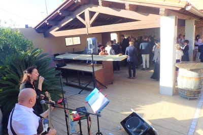 Miniature DJ Pézilla-la-Rivière (Pyrénées-Orientales) - Cleanjack #7 Un duo musical se produit sur une scène intérieure avec guitare et chant, devant un public assis.