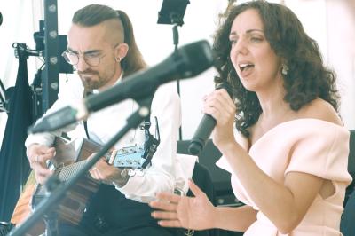 Un groupe de musiciens et une chanteuse se produisent sur scène sous des lumières colorées.