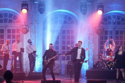 Un groupe de musiciens et une chanteuse se produisent sur scène sous des lumières colorées.