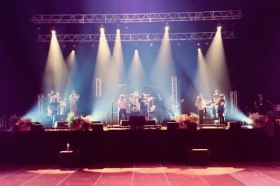 Un groupe de musiciens et une chanteuse se produisent sur scène sous des lumières colorées.