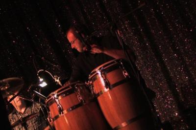 Un groupe de musiciens et une chanteuse se produisent sur scène sous des lumières colorées.